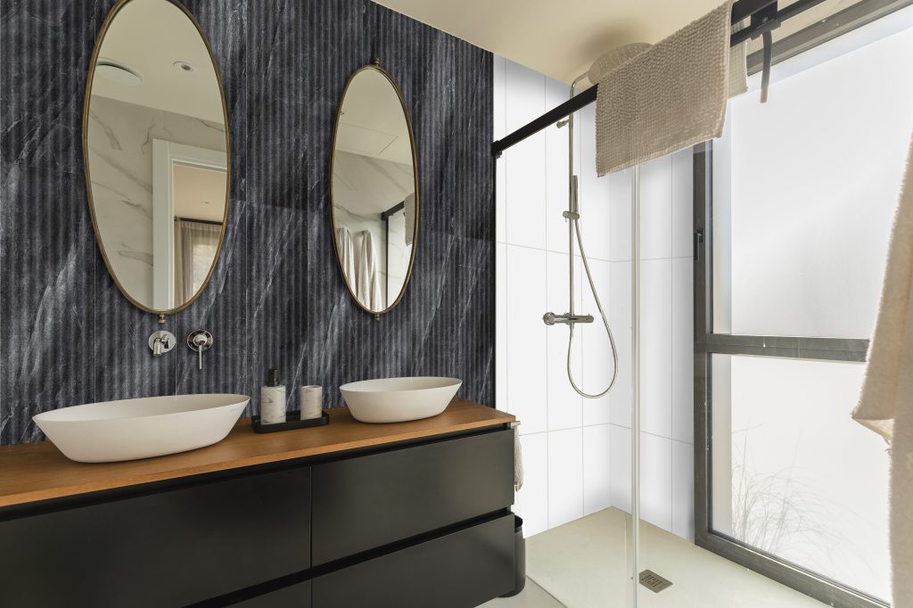 Baño moderno con revestimiento oscuro en muro principal, tendencia de muros con carácter para 2026.